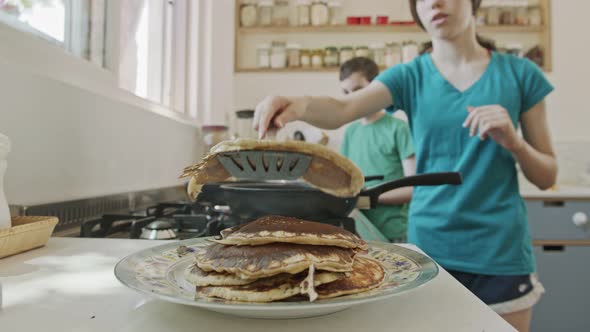 Young kids preparing pancakes in the kitchen using a frying pan