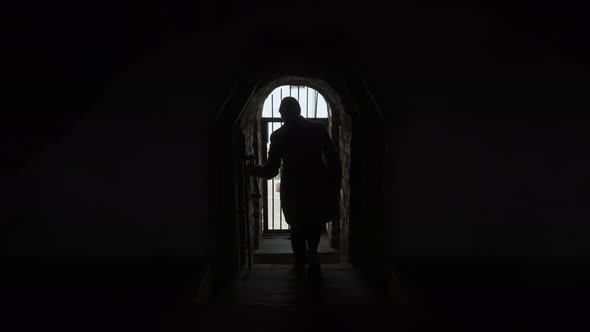 Woman in Coat Descends Steep Wooden Stairs of Old Medieval Castle