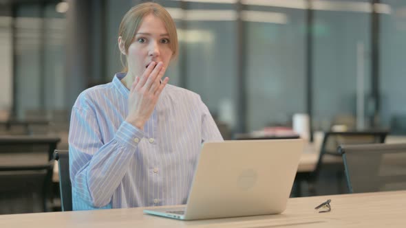 Young Woman Feeling Shocked While Using Laptop in Office