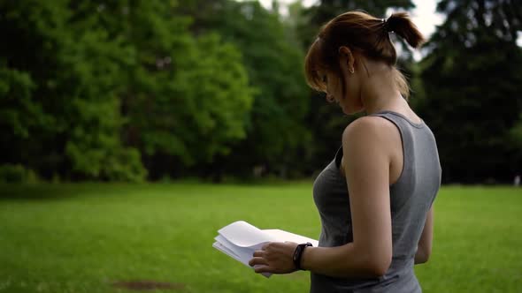 Girl Leafing Through a Book in Nature Day