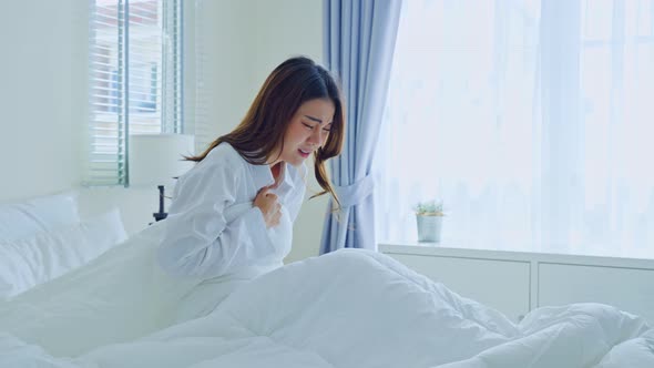 Attractive young woman feeling bad after wake up on bed and coughing in early morning at home.