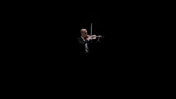 Young Caucasian Male in Black Suit and Glasses Plays Violin on Dark Background