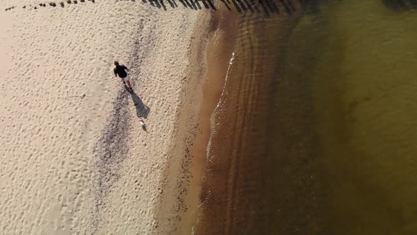 Man with Dog Runs Along the Beach