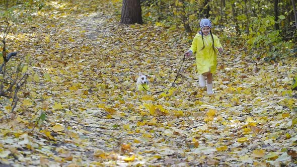 Concept of Pets, Family and Friendship. Little Girl with a Dog Running in the Autumn Park