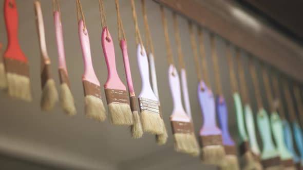 Many Pastel Color Brushes Hang on Ropes From Ceiling