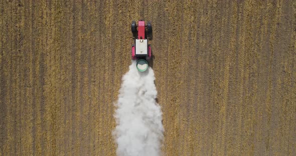 A Tractor Drives Fertilizer Across A Mown Field 