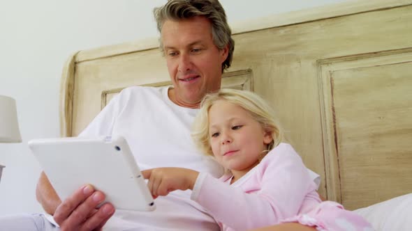 Smiling father and daughter using digital tablet on bed 4k