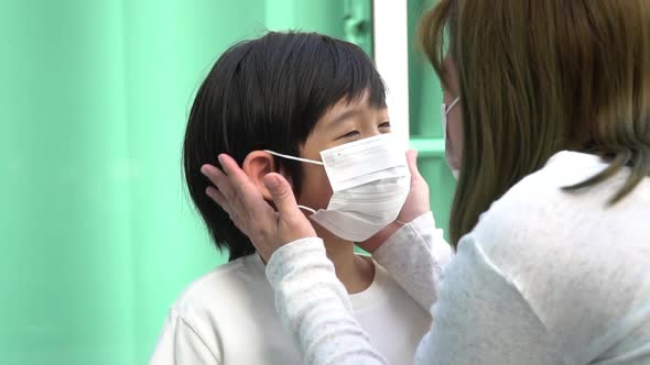 Asian Mother Puts A Safety Mask On Her Son Face