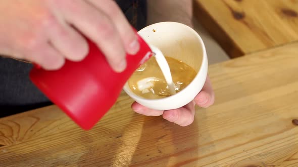 Close-up of Hands Pouring the Warm Milk in Coffee Cup