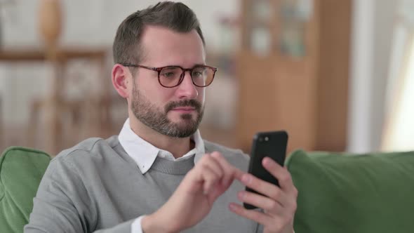 Portrait of Middle Aged Man Using Smartphone on Sofa