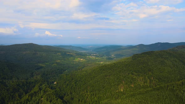 Aerial View of Mountain Hills Covered with Dense Green Lush Woods on Cloudy Evening