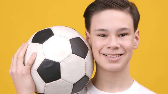 Happy Teen Boy Holding Ball Posing Over Yellow Background