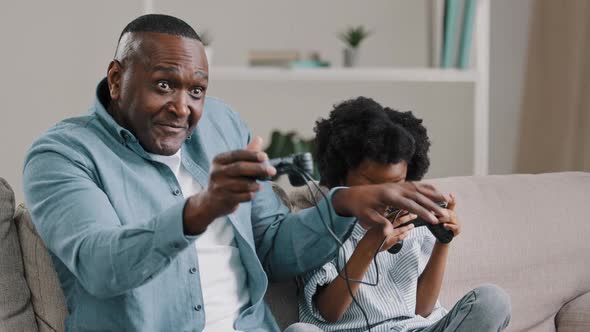 Mature African American Father with Little Daughter Playing Video Games on Console Use Joystick