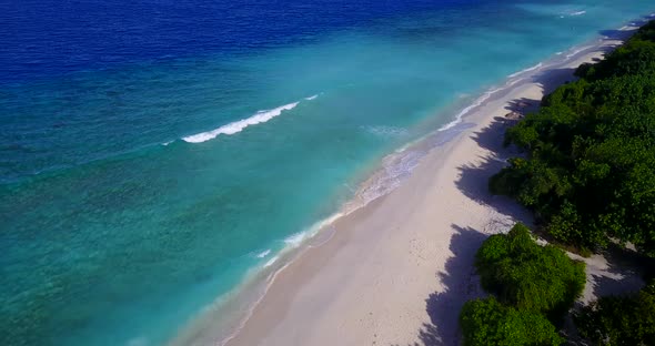 Daytime birds eye island view of a white paradise beach and blue water background in colorful 4K