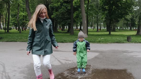 Funny Kid in Rain Boots Playing in a Rain Park