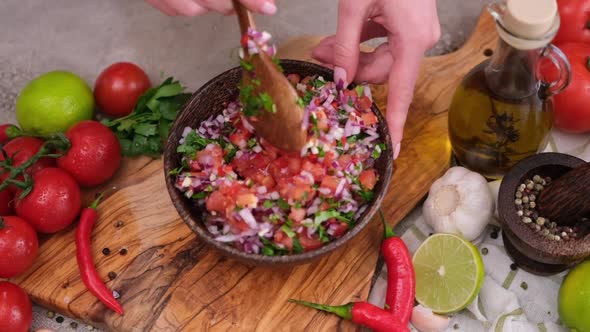 Slow Motion Shot of Woman Mixing Salsa Dip Sauce Ingredients in Wooden Bowl