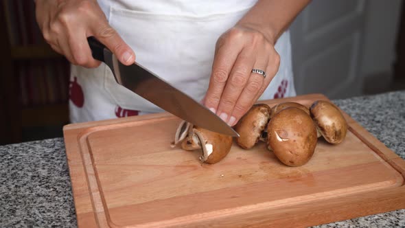 Woman's Hands Slicing Fresh Mushrooms On A Chopping Board. close up