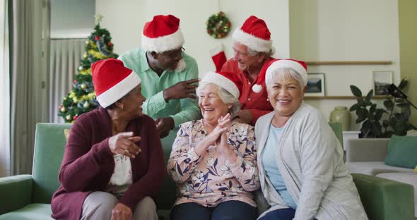 Happy diverse senior friends in santa hats on video call at christmas time