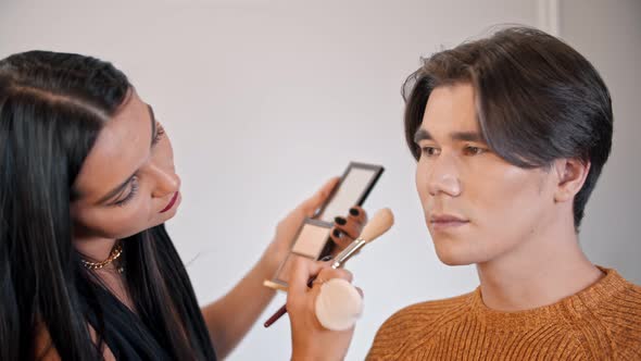 Woman Make Up Artist Applying Contour Shades on the Face of Male Model Using a Brush