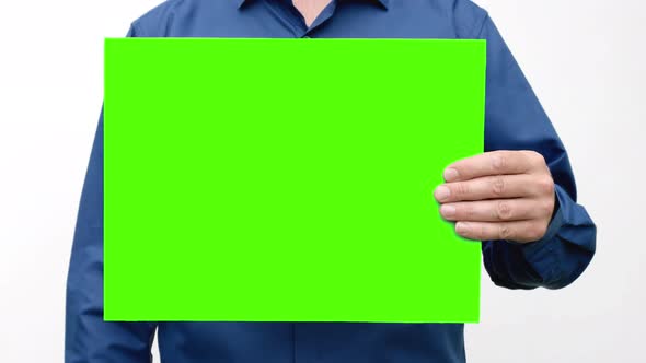 A person holds a green screen in front of him