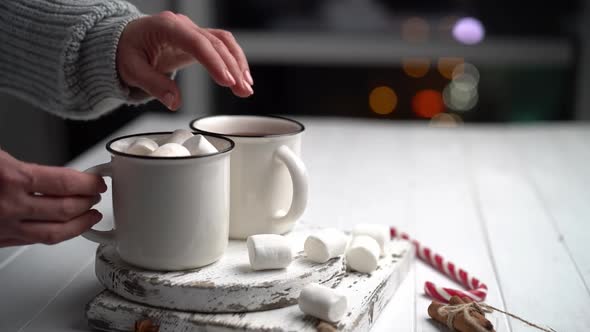 Woman Throwing Marshmallow Into Cocoa Cup