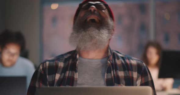 Senior Bearded Man Smiling and Celebrating Success Working on Laptop in Office