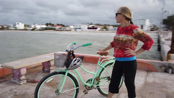 Closeup of mature woman with her face into the wind, holding her bike and looking into the sky and l