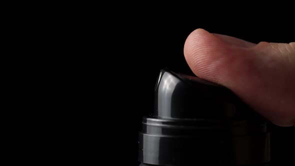 Hand Presses a Spray of Deodorant on a Black Background