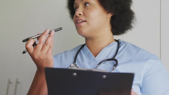 Video of focused plus size african american female doctor using smartphone