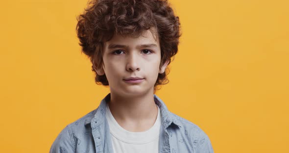 Adorable Boy Smiling at Camera, Studio Portrait Over Orange Background