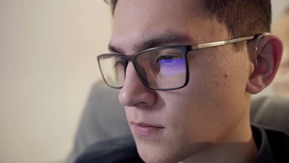 The Laptop Monitor Reflected on the Glasses of a Young Man