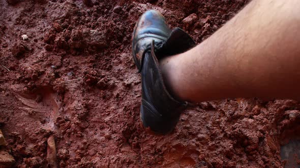 Leg with boot leaving a footprint on mud