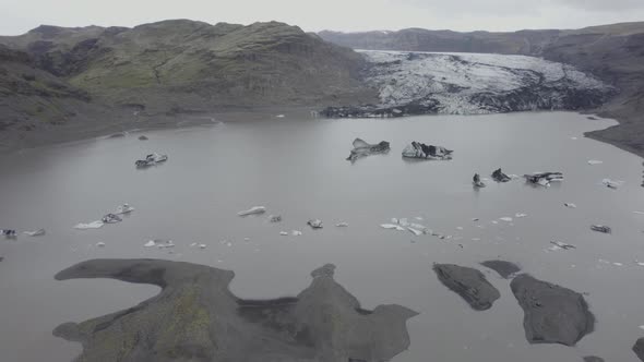 Aerial view overlooking ice blocks and the Solheimajokull glacier - tilt, drone shot