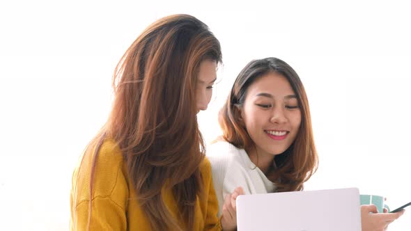 Young Asian lesbian LGBT couple using laptop on bedroom at home.