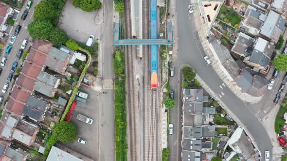 Drone shot over South Western British Rail train leaving a small station