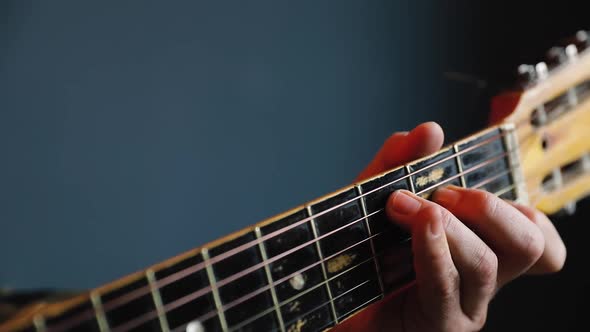 Man Play Acoustic Guitar at Blue Wall Closeup