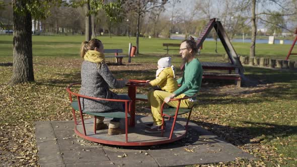 Family playing at merry-go-round in public playground, Zagreb, Croatia.