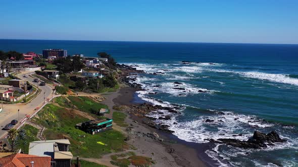 Aerial drone with a view of the beach and people and children playing with a general view of the hou