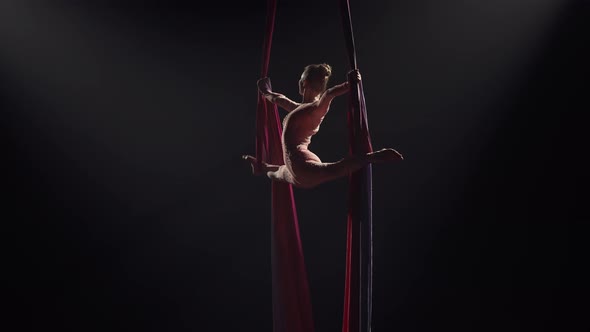Young Female Circus Gymnast Spins on Aerial Silk and Demonstrates Stretching