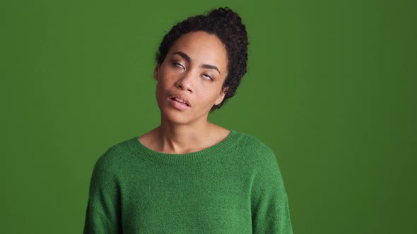 Tired African woman in green shirt showing blah gesture