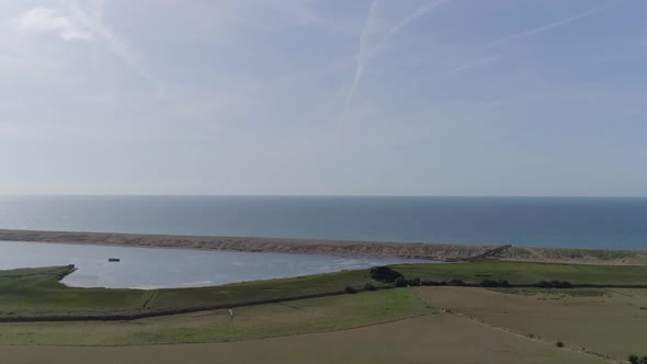 Aerial tracking upward looking out to sea over the fleet lagoon at Abbotsbury, and Chesil beach.