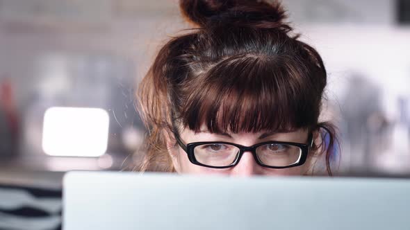 Woman Sits at Home Near a Laptop and Surfs the Internet, Reflection in Glasses Close Up, Moving