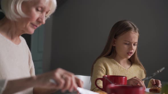 Cheerful grandmother and granddaughter having breakfast