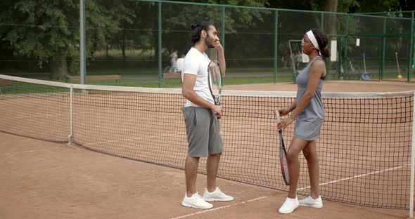 Multiracial Man and Woman Talking on Tennis Court