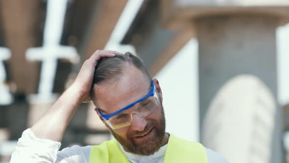 Close Up Portrait of Smiling Young Master Builder in Protective White Hard Hat Looking at Camera