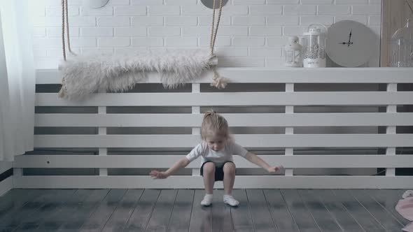 Blonde Girl Toddler Does Exercises in White Background