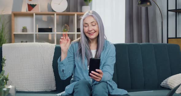 Woman Sitting on Comfortable Sofa at Home and Enjoying Video Chat on Mobile with Friend or Relative