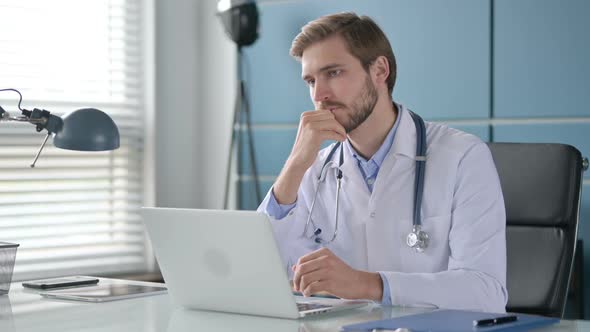 Doctor Thinking While Working on Laptop in Office