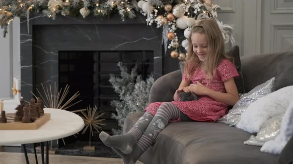 Smiling Little Girl Stroking Kitten in Christmas