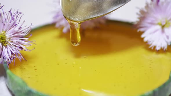 Transparent Honey Pours From a Spoon Into a Lid a Bowl